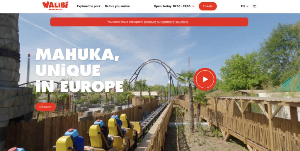 a roller coaster with trees and a blue sky in Walibi Park in France